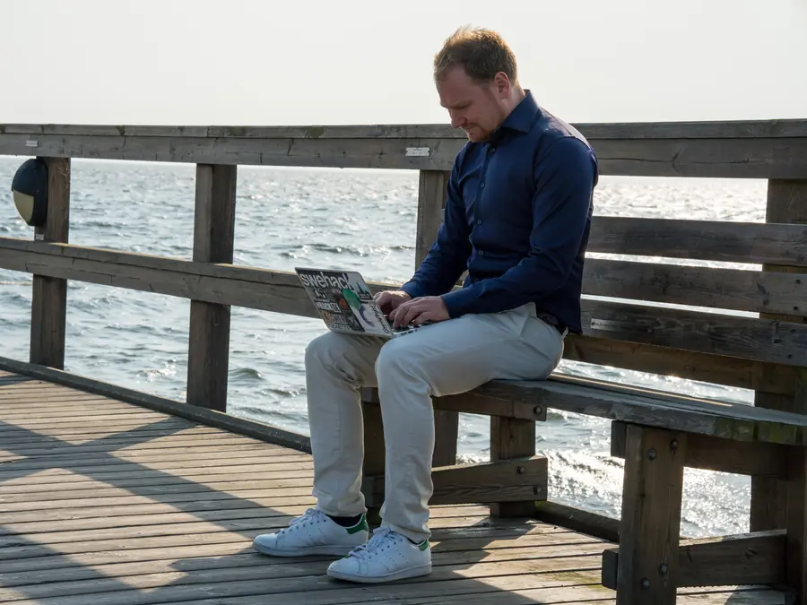 Press photo 12 of David Jacoby: On a pier bench with laptop, wide